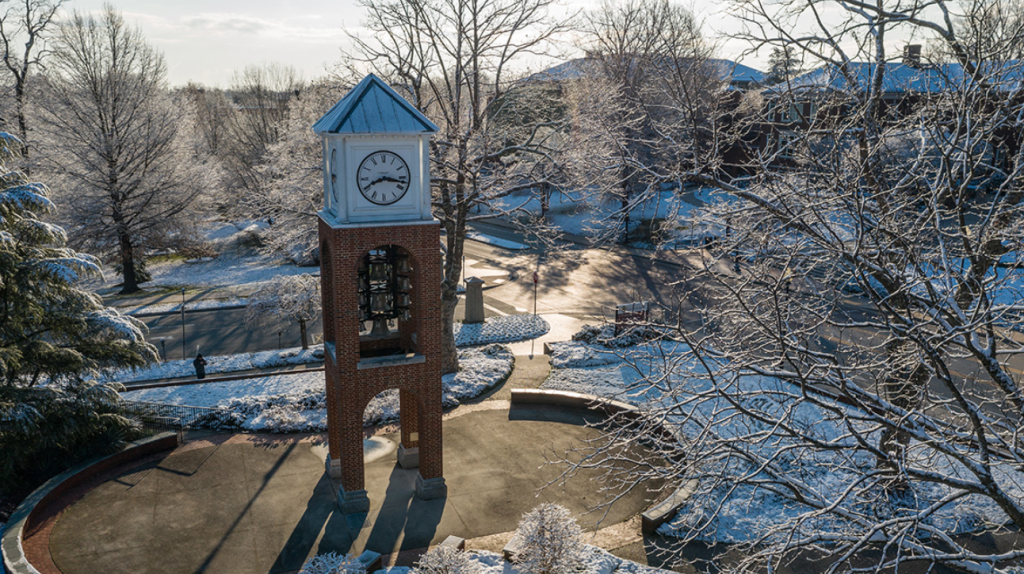 Aerial view of UNCG's campus covered in snow around the bell tower